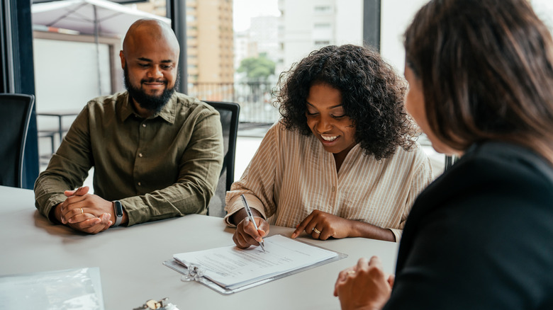 Couple closing real estate contract with real estate agent